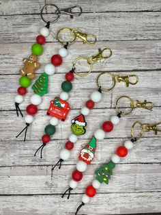 several christmas themed key chains on a wooden table with other items in the shape of santa's helpers