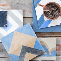 some blue and white tiles on top of a wooden table next to a potted plant