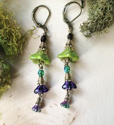 Purple and Green Flower Earrings, Fairy Flower Earrings Some days you need jewel-toned romantic earrings to wear while you read poetry in the garden. These purple and green floral earrings are perfect for adding wistful charm to your look! I made these triple flower earrings with: *mossy green Czech glass flower beads with gold wash *smaller dark purple Czech glass flower beads *tiny purple and green iridescent Czech glass flower beads. The colors shift as you move! *variety of antique golden an Whimsical Nickel Free Dangle Flower Earrings, Green Bohemian Flower Earrings For Gift, Botanical Style Green Flower Jewelry, Green Earrings With Flower Charm For Jewelry Making, Bohemian Flower Earrings With Birth Flower Details, Whimsical Green Dangle Earrings, Bohemian Dangle Earrings With Birth Flower, Bohemian Flower Earrings With Birth Flower, Whimsical Green Flower Jewelry