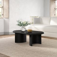 a living room with a white couch and black coffee table in front of a window