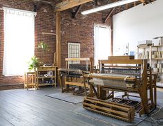 an old weaving machine is in the middle of a room with brick walls and windows