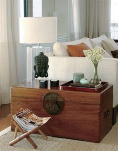 a wooden trunk sitting on top of a floor next to a table with a vase