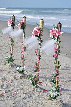 wedding decorations on the beach with pink flowers and white tulle, along with candles