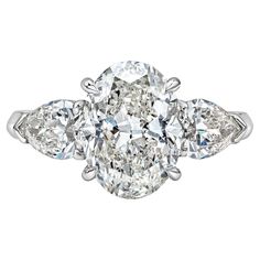 an oval diamond ring with three pear shaped diamonds on the shoulders and side stones, set in