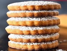 a stack of powdered sugar donuts sitting on top of a wooden table