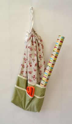 an orange pair of scissors is in a green bag with polka dots and flowers on it