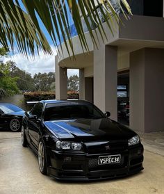 two black cars parked next to each other in front of a building with palm trees