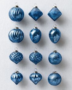 twelve blue christmas ornaments hanging on a white wall