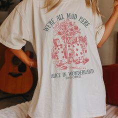 Get ready to be OBSESSED with your new Alice in Wonderland Lewis Carroll Mad Hatter shirt. It's the cutest and most trendy way to combine all those important trendy dark academia and literature shirt vibes! This is the perfect disneyworld shirt!  * Q U I C K * F A C T S * ✺  All shirts are UNISEX ✺  100%  ringspun cotton (fiber content may vary for different colors) ✺  Soft-washed, garment-dyed fabric brings extra coziness ✺  Wash and dry normally (on cool for best results) ✺  Sewn-in twill label * S I Z I N G * ✺ For an oversized fit, select two or three sizes up from your normal size ✺ Model is wearing size L  ✺ Sizing runs true to size ✺ Relaxed fit ✺ Most women find their typical size works best, since they are meant to fit a touch loose ✺ See Size guide and fit in images          * S Alice In Wonderland T Shirt, Bookish Relaxed Fit Graphic Print Top, Relaxed Fit Bookish Tops With Text Print, Bookish Short Sleeve T-shirt For Spring, Spring Bookish Style Short Sleeve T-shirt, Spring Bookish Short Sleeve T-shirt, Bookish Short Sleeve Screen Print Tops, Relaxed Fit Graphic Print Shirt With Bookish Style, Relaxed Fit Graphic Print Shirt In Bookish Style