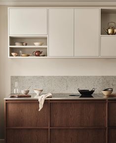 a kitchen with white cabinets and wooden counter tops, along with dishes on the shelves