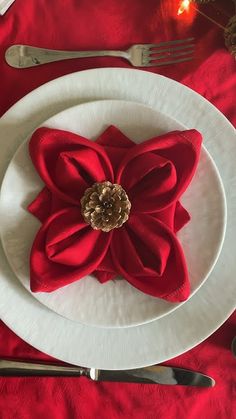 a white plate topped with a red flower next to silverware and utensils