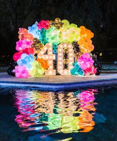 the number ten sign is lit up in front of a pool with balloons and streamers