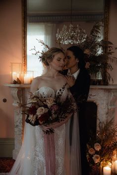 the bride and groom are kissing in front of a fireplace