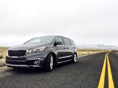 a car is parked on the side of the road in front of an empty field