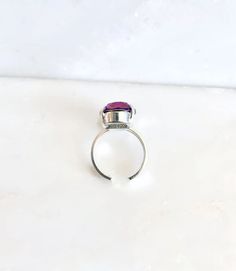 This stunning crystal cocktail ring is sure to turn heads! A gorgeous 18mm oval crystal is set in a luxurious, adjustable gold plated ring band that can fit sizes 5 and up. This 12-carat gem is perfect for any special occasion or for adding an eye-catching sparkle to your everyday look. As the light catches it, the crystal gleams in a shades of blue, purple, and pink. The ring base is nickel free! Ships Free • Handmade in the USA Oval Ruby Ring For Parties, Oval Ruby Ring For Party, Pink Oval Rings For Party, Oval Gemstone Party Rings, Oval Gemstone Rings For Party, Adjustable Oval Jewelry For Party, Adjustable Oval Party Jewelry, Adjustable Crystal Ring With Stone Setting For Promise, Adjustable Pink Ruby Ring