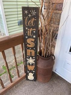 a wooden sign that says let it snow next to a potted plant on the porch