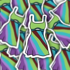 a dress sticker sitting on top of a pile of colorful clothing pieces in the background