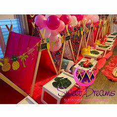 a room filled with lots of tables covered in pink and yellow balloons, pineapples and other decorations