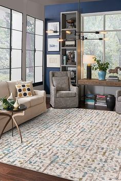 a living room with two couches and a rug on the floor in front of large windows