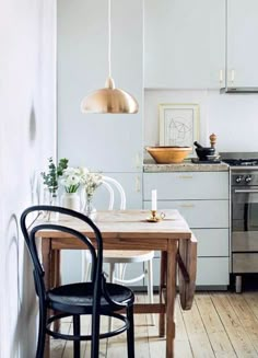 a table and chairs in a small kitchen with an oven on the wall behind it