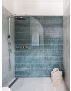 a blue tiled bathroom with a shower and toilet