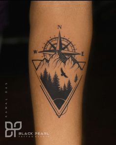 a man's leg with a compass and pine trees tattoo on the side of his calf