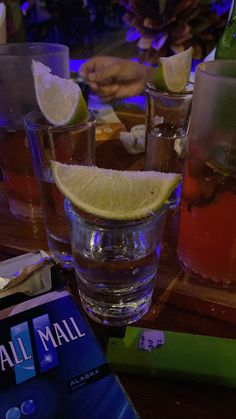 there are three glasses with lemons and water on the table next to each other