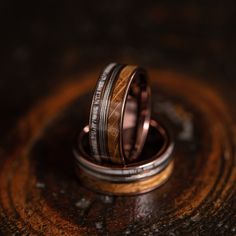 two wedding bands with wood inlays are on top of an old wooden table