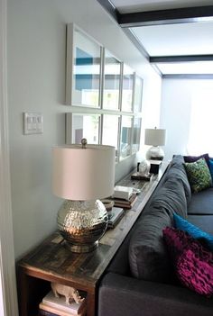 a living room filled with furniture and a large mirror on top of the wall above it