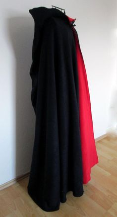 a black and red cloak is hanging on a white wall next to a wooden floor