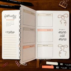 an open planner book on a table with pens and markers