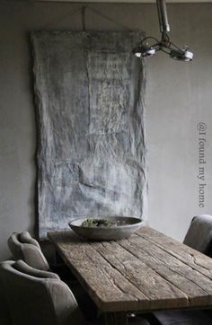 a wooden table with two chairs and a bowl on it in front of a painting