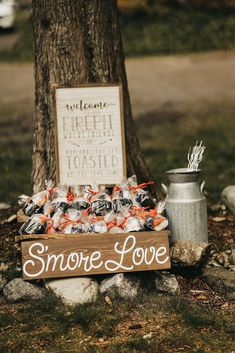 a sign that says s'more love next to a tree