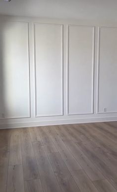 an empty room with white walls and wood floors