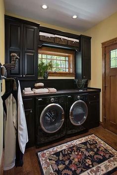 a washer and dryer in a room with dark wood cabinets, rugs and windows