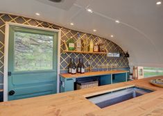 the inside of an airstream with wooden counter tops and shelves filled with wine bottles