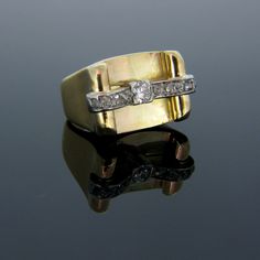 a gold ring with two diamonds sitting on top of a reflective surface in front of a black background