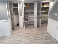 an empty walk in closet with wooden floors and white cabinets on either side of the closet doors