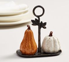 two small white and orange pumpkins sitting on a plate next to a black hook