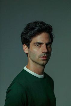 a man in a green sweater is looking at the camera with an intense look on his face