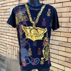 Vintage Christian Audigier Famed For Y2k Fashions Ed Hardy And Von Dutch Lines Features Gold Wings And Logo On Front And Metallic Gold Skulls And Below “All You Need Is Love” Black Shirt Size Large Black All Over Print Tops For Streetwear, Black Tops With All Over Print For Streetwear, Black Y2k Style Crew Neck Shirt, Black Y2k Shirt With Letter Print, Black Y2k Shirt With Crew Neck, Y2k Black Tops With Logo Print, Black Y2k Top With Sublimation Print, Black Y2k Tops With Logo Print, Tan Logo Print Shirt For Streetwear