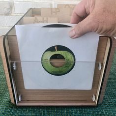 a person holding an apple in front of a record player's box with the label on it