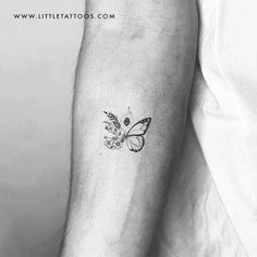 a black and white photo of a butterfly tattoo on the left inner arm, with an arrow