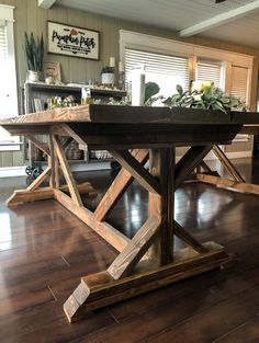 a wooden table sitting on top of a hard wood floor covered in potted plants