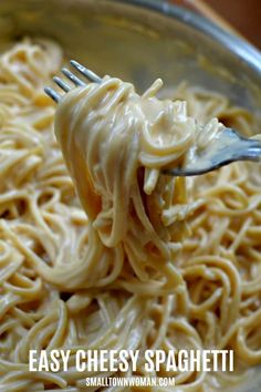 a fork full of pasta being held by someone's hand with the word easy cheesy spaghetti on it