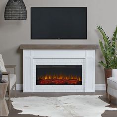 a living room with a fireplace and television mounted on the wall, in front of a plant