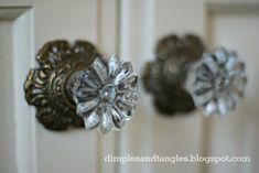 three metal knobs are attached to a white door with gold trim and silver flowers