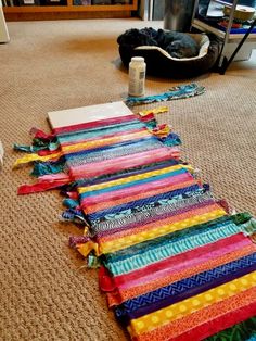 a cat is laying on the floor next to a pile of colorful ribbons