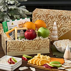 an assortment of fruit, cheese and crackers in a gift box on a table