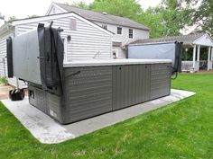 an outdoor hot tub sitting on top of a cement slab in front of a house